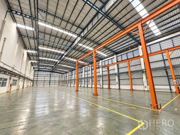 Factory for sale in Lam Luk Ka, Pathum Thani - Expansive warehouse area with multiple crane columns and a large roller door.