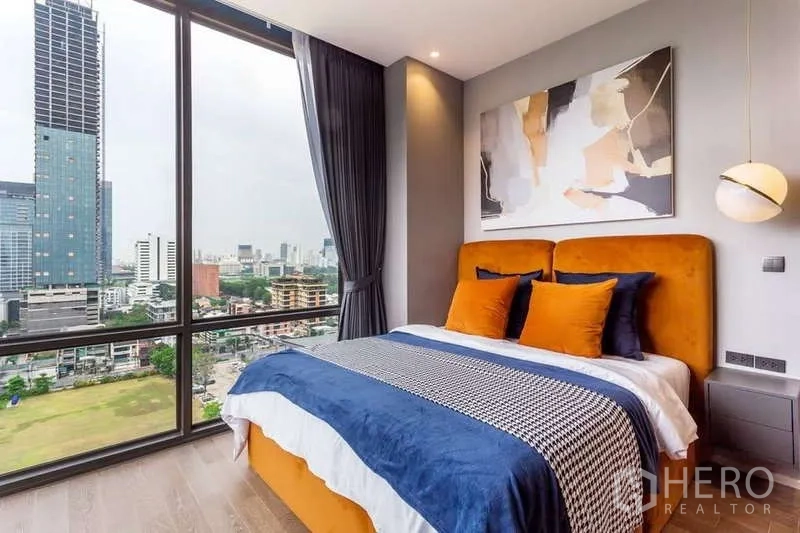 Condominium for rent in Pathum Wan, Bangkok - Second bedroom with orange headboard and panoramic city view near Lumpini Park.