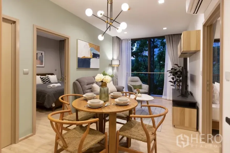 Condominium for rent or sale in Watthana, Bangkok - Dining space facing the living room and large balcony with evening garden views.