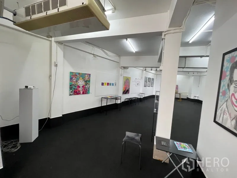Shophouse for rent in Khlong Toei, Bangkok - Long gallery space with white walls, track lighting and displayed artwork.