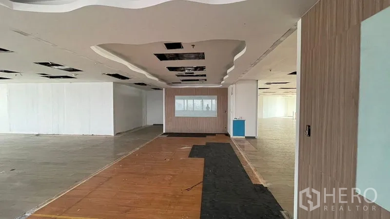 Office Space for rent or sale - Open office zone featuring a wavy drop ceiling, wood accent wall, and mixed flooring.