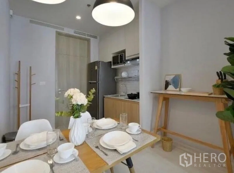 Condominium for rent in Pathum Wan, Bangkok - Cozy dining corner beside a compact kitchen with full-size refrigerator and modern lighting.