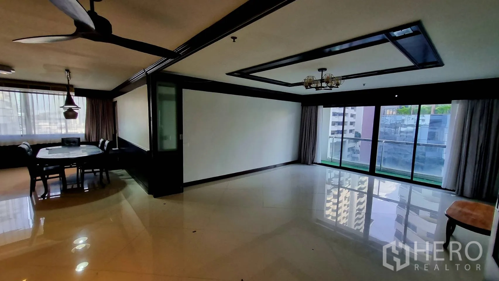 Condominium for rent in Watthana, Bangkok - Open living–dining room with sliding doors to a city-view balcony.