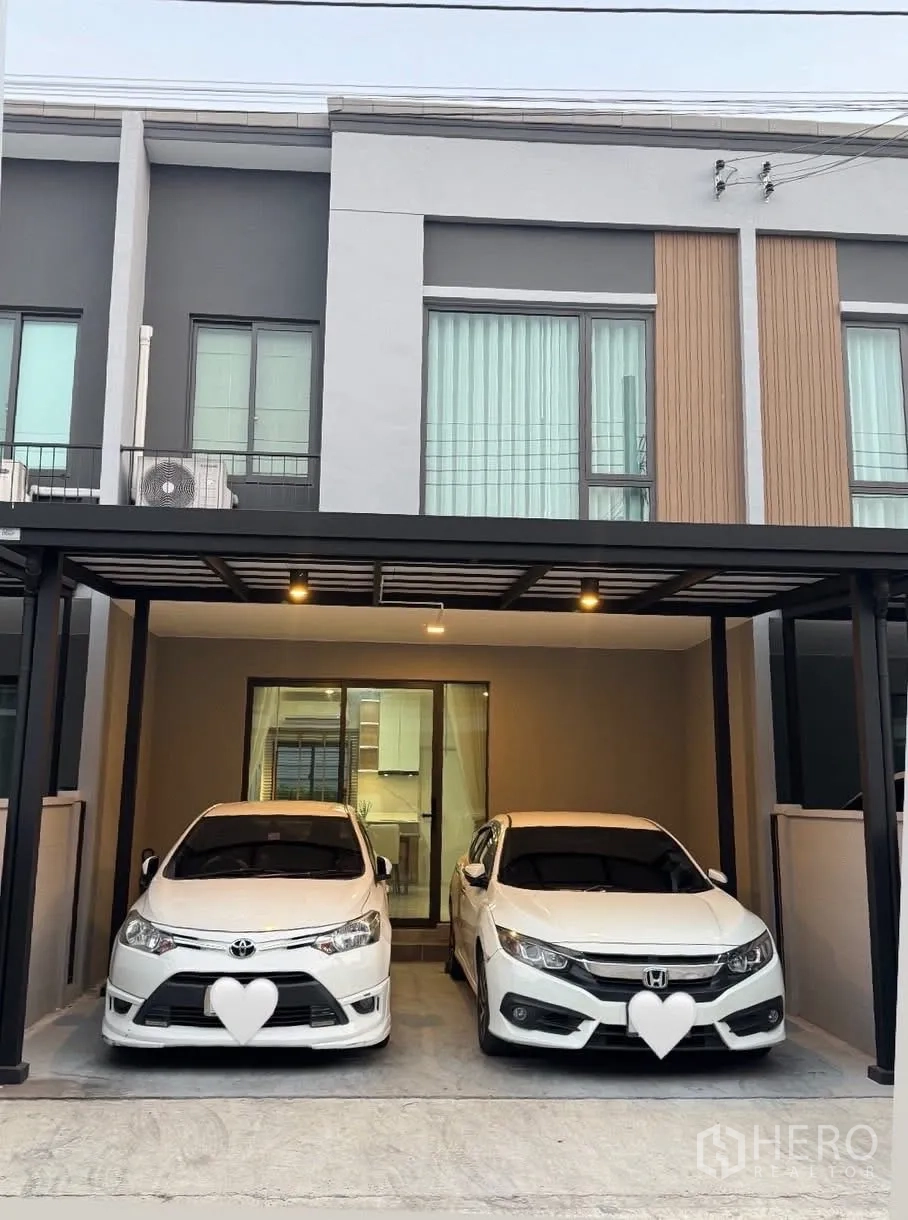 ทาวน์เฮาส์ for rent in Bang Phli, Samut Prakan - ด้านหน้าทาวน์เฮ้าส์สองชั้นสไตล์โมเดิร์นพร้อมโรงจอดรถในร่ม 2 คันและประตูกระจกบานเลื่อน.