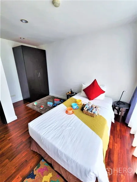 Condominium for rent in Bang Rak, Bangkok - Cozy bedroom with a single bed, dark wardrobe, and polished wooden floors.