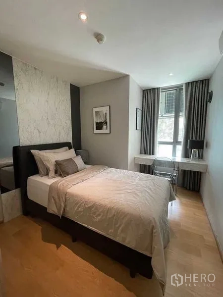 Condominium for rent in Watthana, Bangkok - Cozy bedroom with double bed, wall art, work desk by the window, and wood flooring.