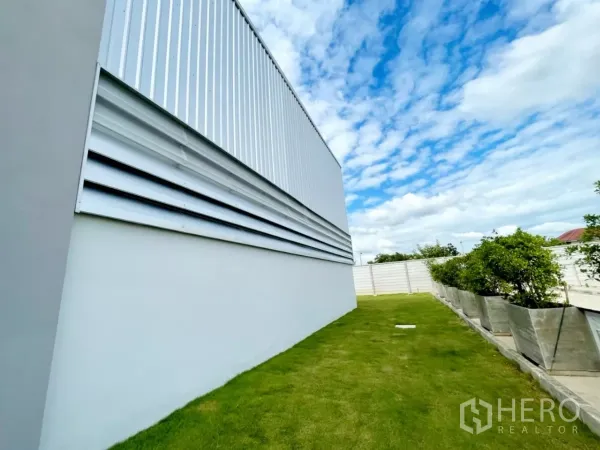 货栈 出售在Lam Luk Ka, Pathum Thani - 仓库外墙百叶与整洁草地、花盆的近景。