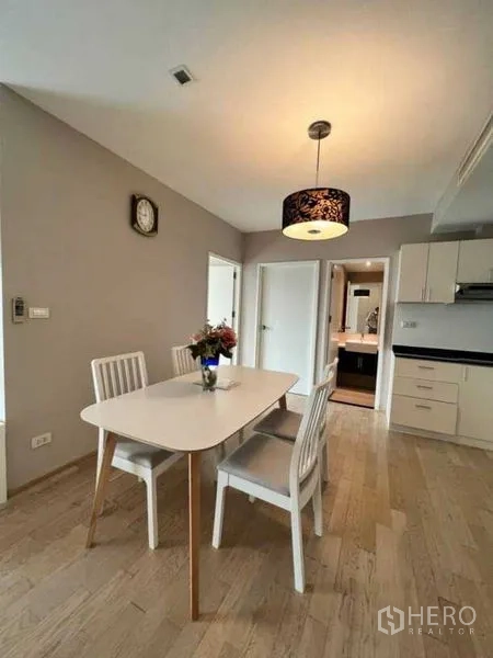 Condominium for rent in Khlong Toei, Bangkok - Dining area for four with pendant light beside an open kitchen.