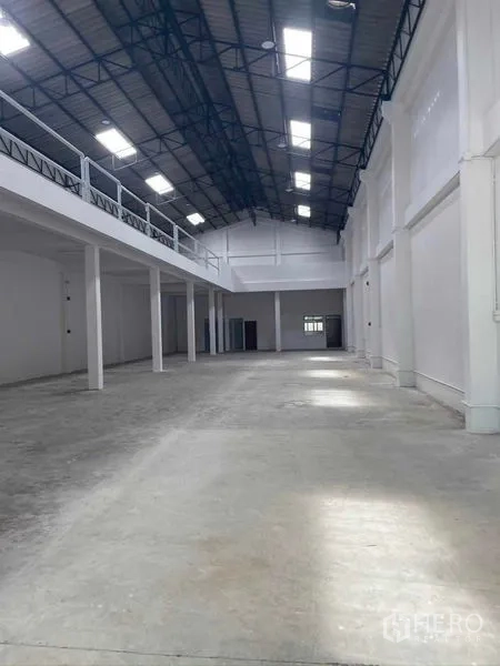 Warehouse for rent in Mueang Samut Sakhon, Samut Sakhon - Open clear-span warehouse bay with white columns, polished concrete floor and long mezzanine.