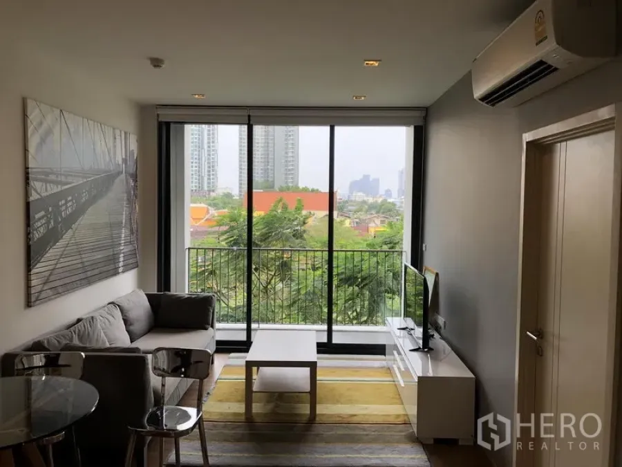 คอนโด ให้เช่าในWatthana, Bangkok - ห้องนั่งเล่นสว่าง พร้อมกระจกเต็มบานและระเบียงวิวต้นไม้ในเมือง