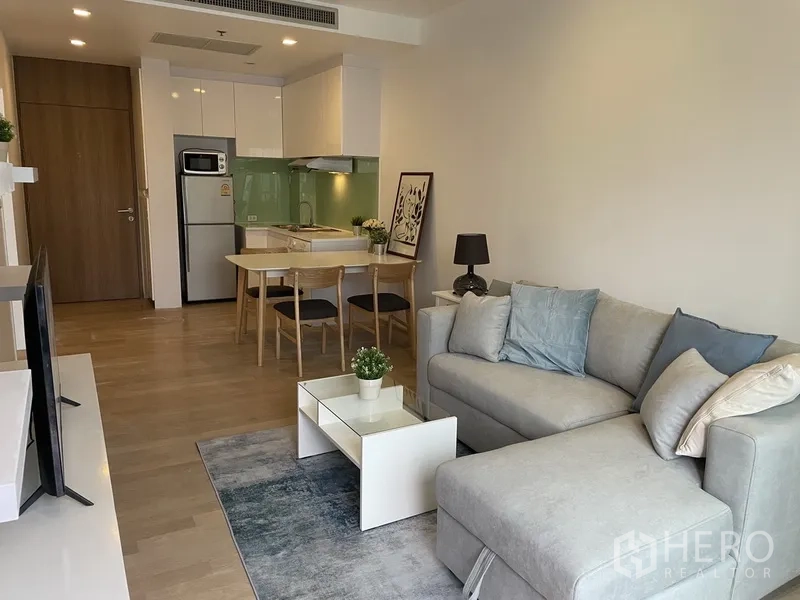 Condominium for rent in Bangkok - Open-plan lounge with dining table and compact kitchen in neutral tones.