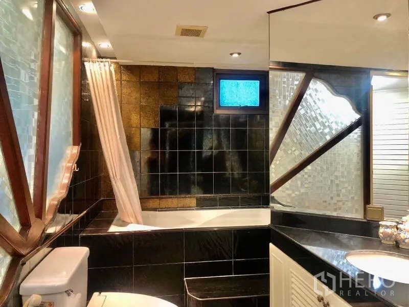 Condominium for rent in Watthana, Bangkok - Bathroom with black tiles, bathtub-shower combo, large mirror and vanity
