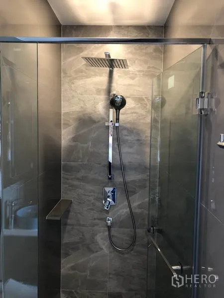 Condominium for rent in Watthana, Bangkok - Modern shower room with glass enclosure, rain shower head and gray stone tiles.