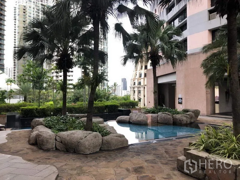 Condominium for rent in Khlong Toei, Bangkok - Condominium facilities with tropical landscaped pool, palm trees and natural boulders.