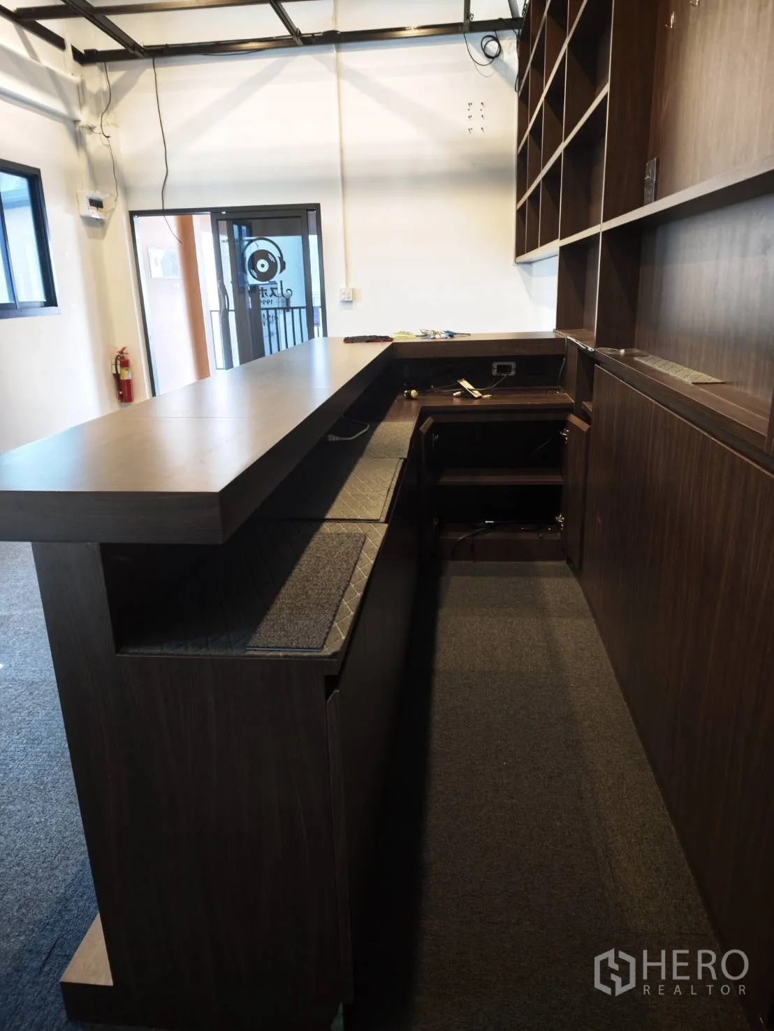 零售空间 for rent in Watthana, Bangkok - 店内长木质吧台与展示搁架的近景。