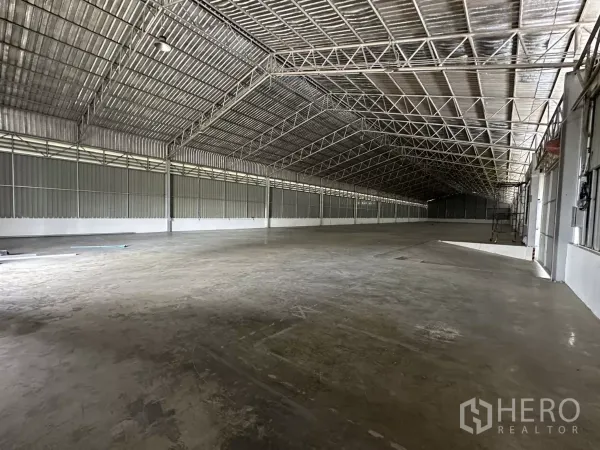 Warehouse for rent in Lat Krabang, Bangkok - Open warehouse hall showing high ceilings, steel beams and expansive loading area along the side walls.