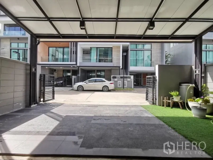 Townhouse for sale - Covered carport with small garden facing a row of modern townhouses.