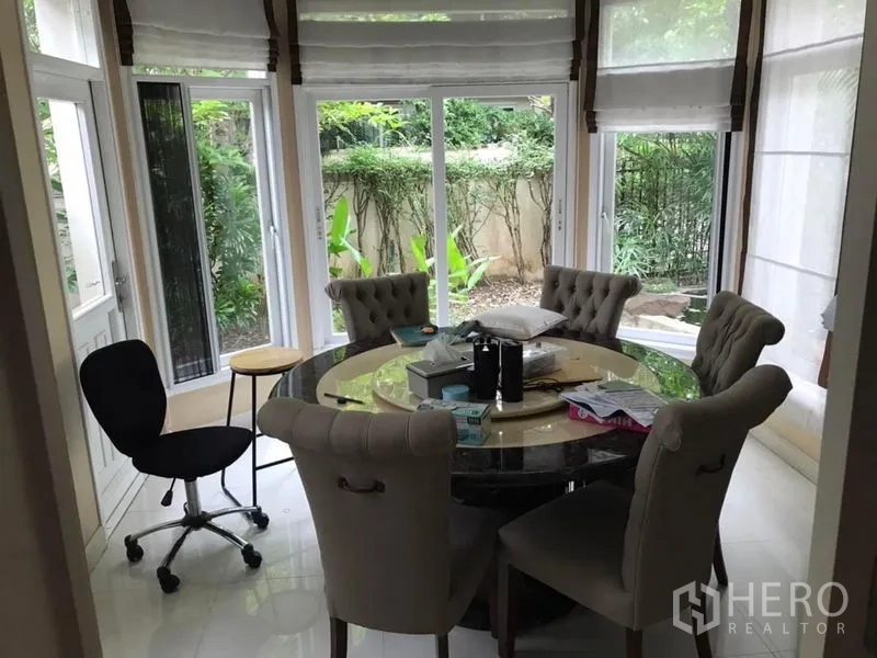 独立式住宅 出租在Bang Khen, Bangkok - 弧形落地窗餐角，圆桌与软包餐椅，可观花园。