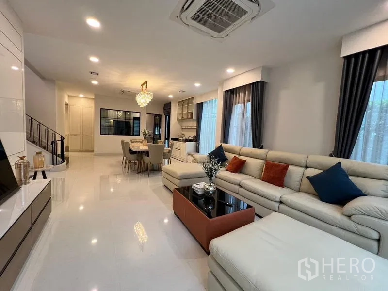 Detached House for rent or sale in Saphan Sung, Bangkok - Open-plan living and dining space with staircase and an oversized sofa.