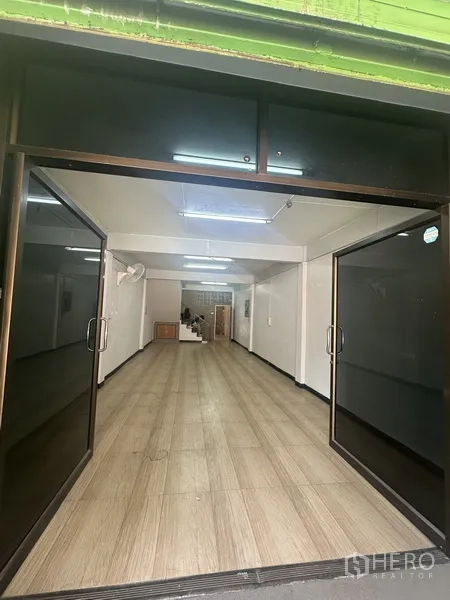 Shophouse for rent or sale in Phra Khanong, Bangkok - Open-plan ground floor retail area with wood-look flooring and wide glass sliding doors.