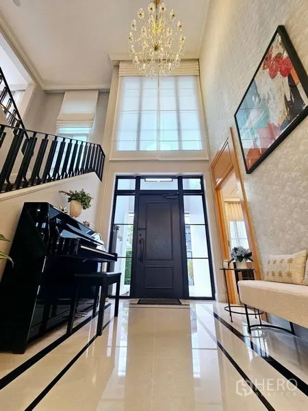 Detached House for rent or sale in Saphan Sung, Bangkok - Double‑height foyer with grand chandelier, piano and staircase.