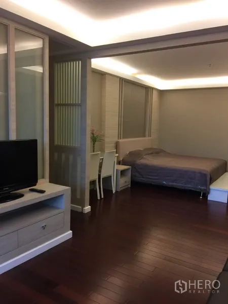 Condominium for rent in Bang Rak, Bangkok - Spacious second bedroom with sliding partition, TV console and study desk on wood floors.