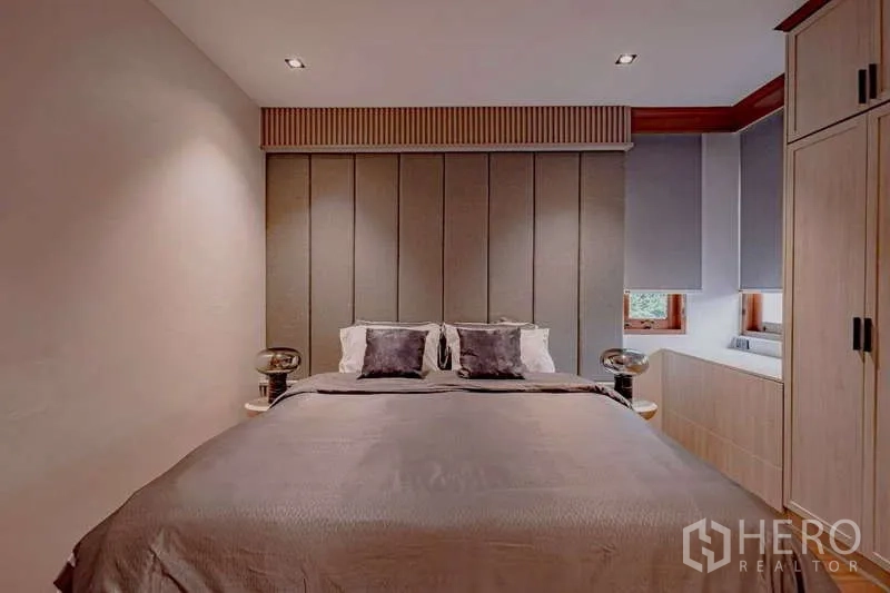 Detached House for rent or sale in Phra Khanong, Bangkok - Cozy guest bedroom with padded headboard, side tables, and built-in storage.