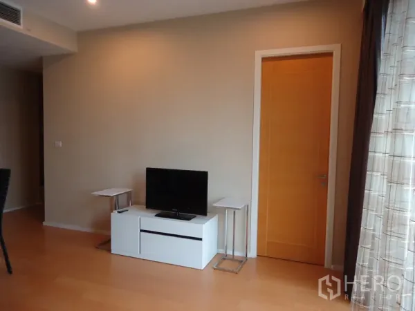 Condominium for rent in Chatuchak, Bangkok - Bright living area with TV console, side tables, light wood flooring and a solid-wood door.