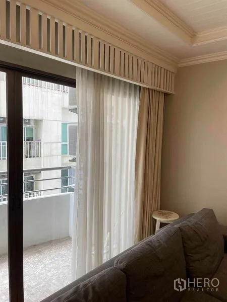 公寓 出售在Watthana, Bangkok - 推拉玻璃门通向小阳台，薄纱窗帘与城市景观。