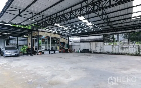 Warehouse for rent in Bueng Kum, Bangkok - Large covered concrete yard with a high steel roof for parking and loading.
