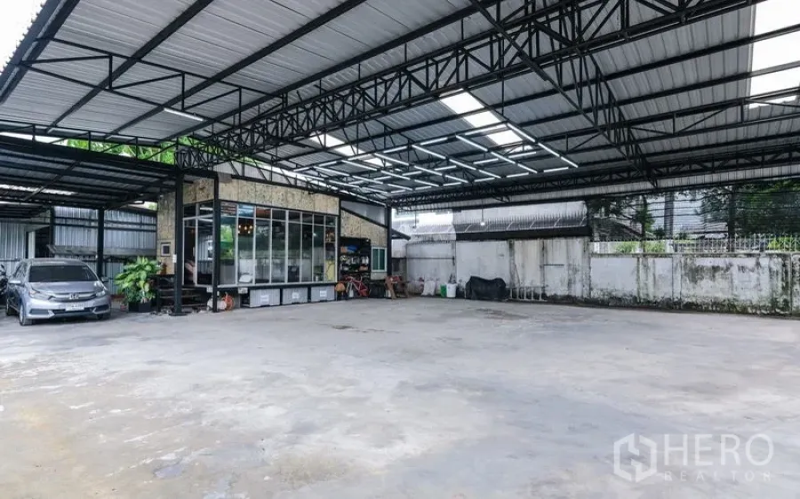 Warehouse for rent in Bueng Kum, Bangkok - Large covered concrete yard with a high steel roof for parking and loading.