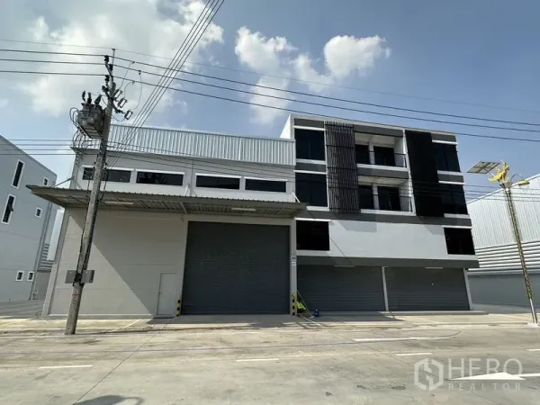 คลังสินค้า ให้เช่าในBang Phli, Samut Prakan - ด้านหน้าโกดังติดถนนพร้อมชานโหลดมีหลังคาและประตูม้วนขนาดใหญ่