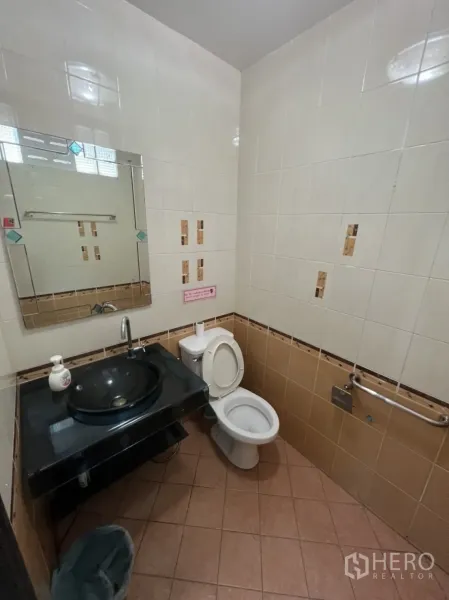 Shophouse for rent in Khlong Toei, Bangkok - Tiled restroom featuring a black countertop sink, toilet and wall mirror.