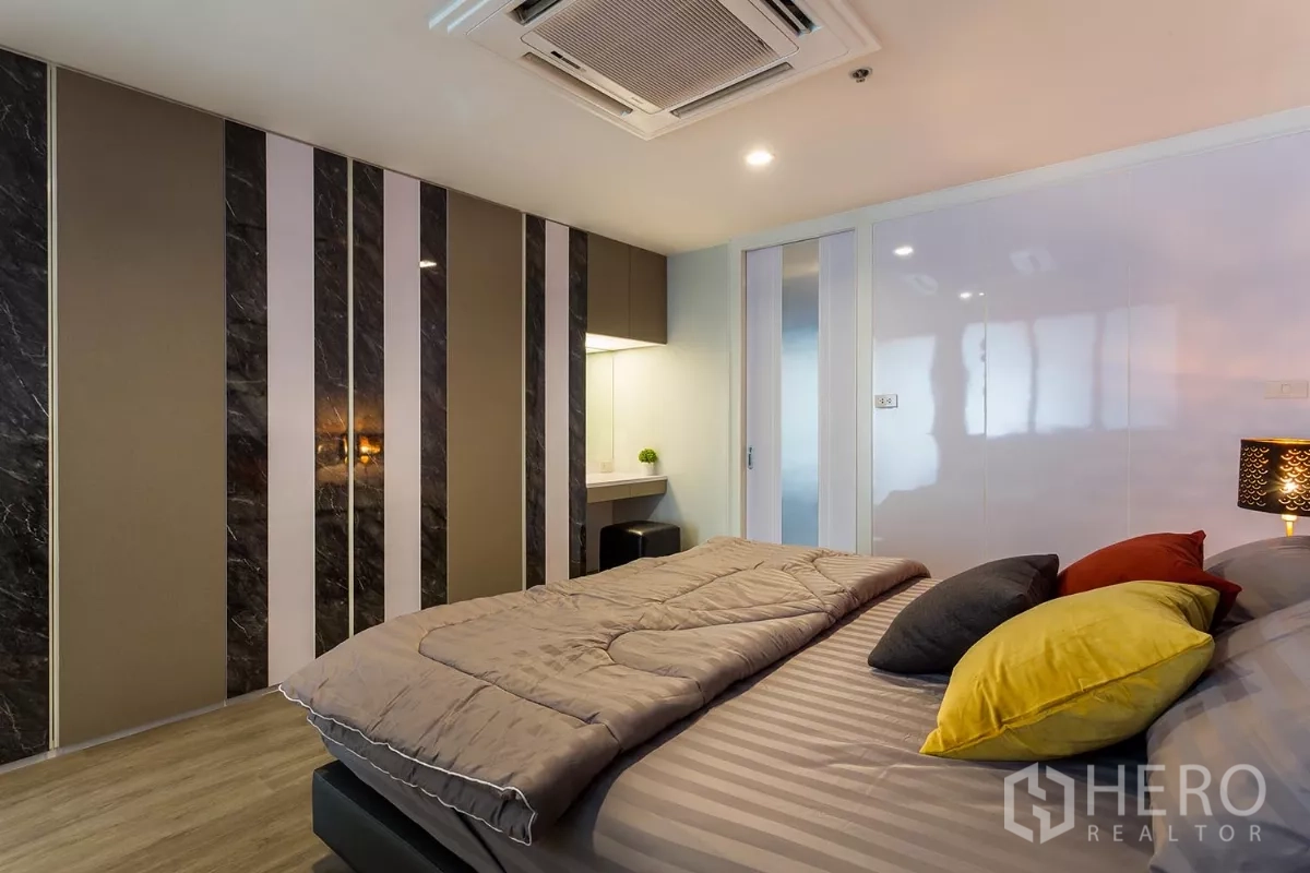 Condominium for rent or sale in Watthana, Bangkok - Bedroom accent wall with vertical marble panels and a built-in vanity.