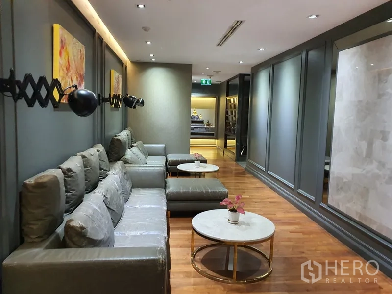 Office Space for rent in Khlong Toei, Bangkok - Cozy waiting area with sectional sofa, wall lamps and marble-topped tables.