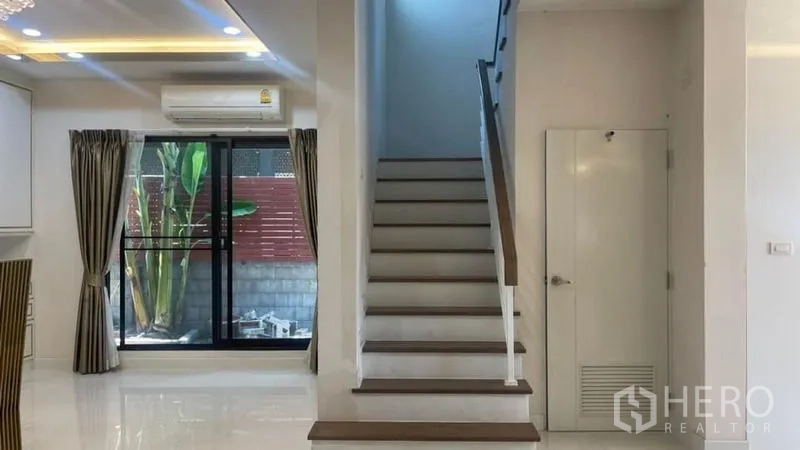 Detached House for rent or sale in Prawet, Bangkok - Staircase with under-stair storage and a sliding door opening to the side garden.
