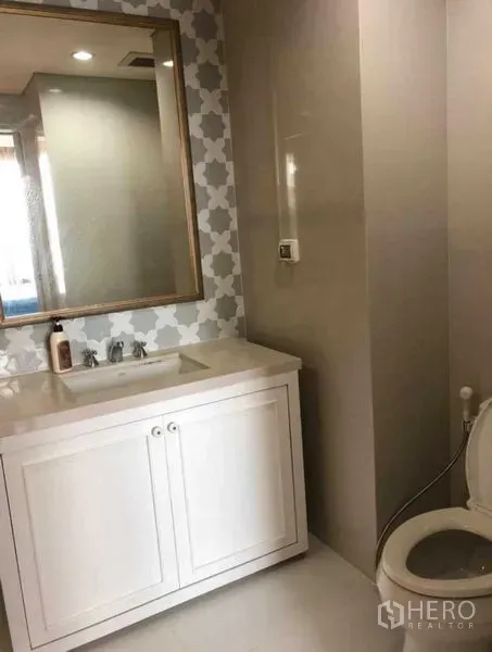 Condominium for sale in Khlong Toei, Bangkok - Bathroom angle showing white vanity, patterned wall tiles and toilet.