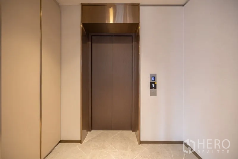 Condominium for rent in Pathum Wan, Bangkok - Private lift lobby with wooden elevator doors and marble flooring.