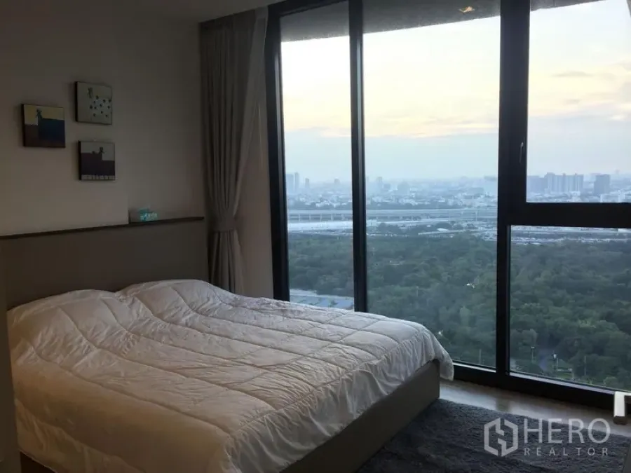 公寓 出租在Chatuchak, Bangkok - 卧室配落地窗，可欣赏公园与城市天际线景观。