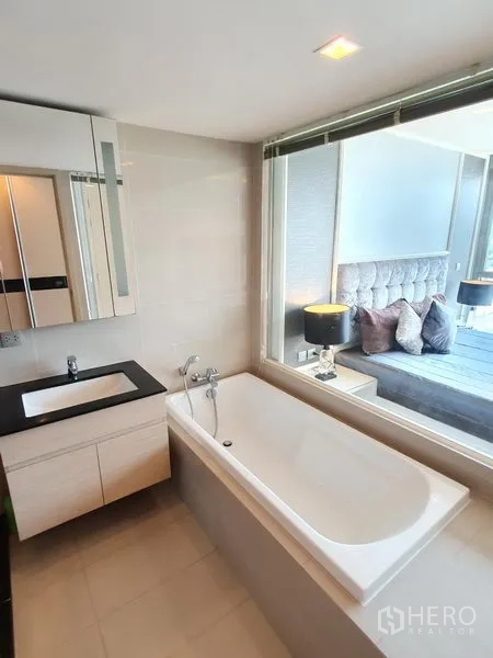 Condominium for rent in Watthana, Bangkok - Bright bathroom with soaking tub, vanity and window looking into the bedroom in a Thonglor-area condo.