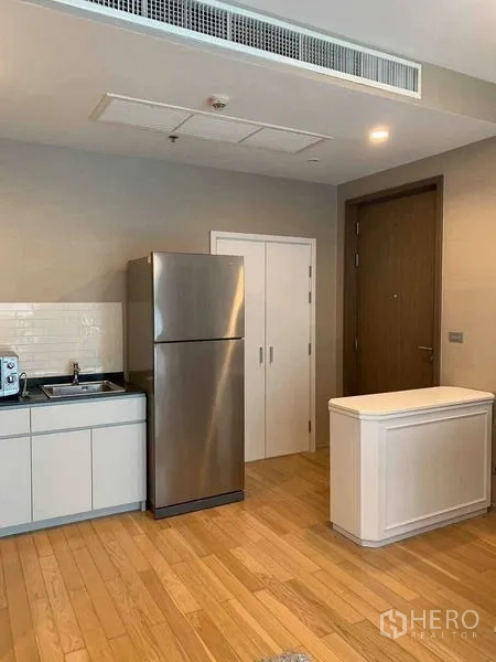 Condominium for sale in Watthana, Bangkok - Entry and kitchenette with sink, tall stainless fridge, storage closet and light wood floors.