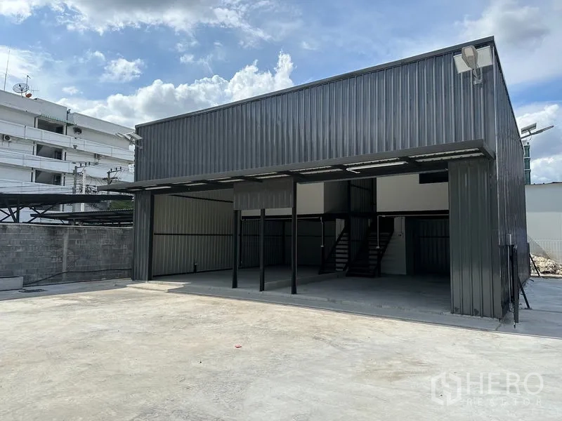 คลังสินค้า ให้เช่า - ด้านหน้าโกดังสมัยใหม่ มีหลังคาคลุมลานขนถ่ายสินค้าและลานคอนกรีตกว้าง