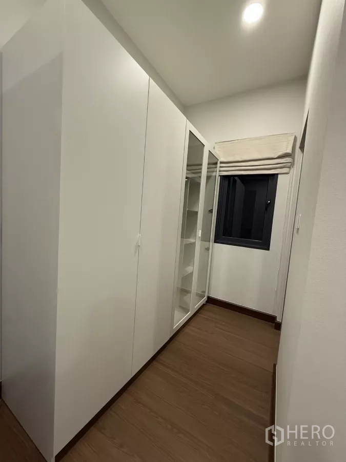 独立式住宅 出租在Bang Phli, Samut Prakan - 步入式衣帽间走廊，白色衣柜与木地板。