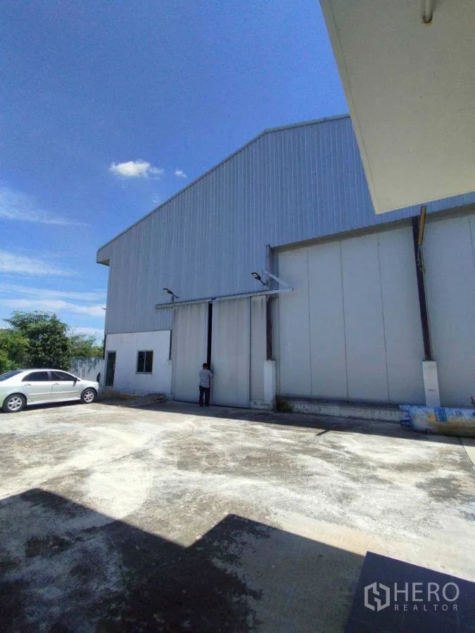 โรงงาน for rent or sale in Mueang Nakhon Pathom, Nakhon Pathom - ภายนอกโรงงานผนังเมทัลชีท ประตูสไลด์ขนาดใหญ่และลานจอดรถกว้าง