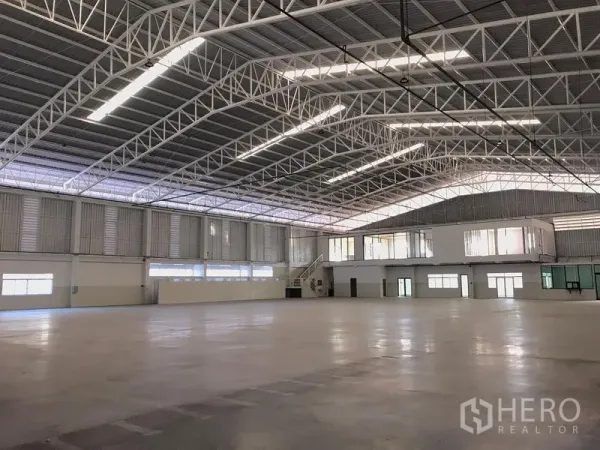 Factory for rent in Mueang Samut Prakan, Samut Prakan - Open production hall with skylights, steel truss ceiling and a mezzanine office with windows.