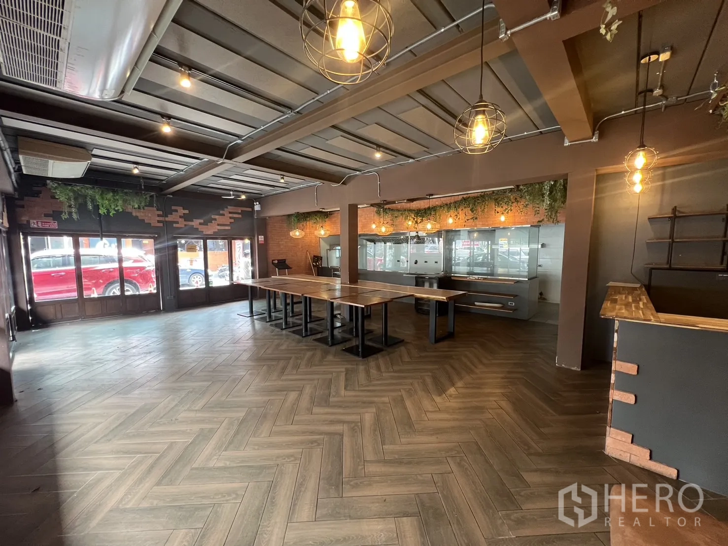 Retail Space for rent in Watthana, Bangkok - Open-plan retail floor with a glass kitchen partition, pendant cage lights and herringbone wood flooring.