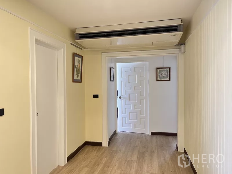 Condominium for rent in Khlong Toei, Bangkok - Hallway with built-in ceiling air conditioner and a geometric white interior door.