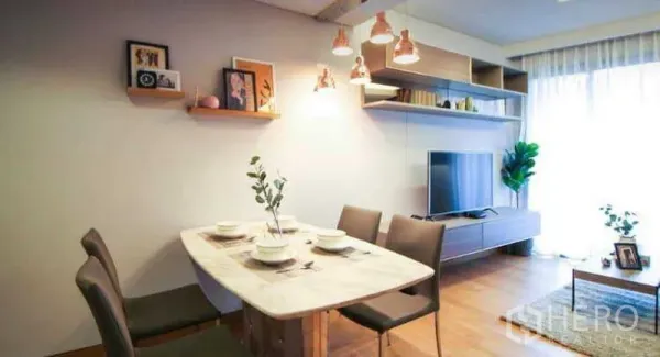 Condominium for rent or sale in Khlong Toei, Bangkok - Bright dining and living area with marble table, pendant lights, floating shelves, TV unit, wood flooring and a large window.