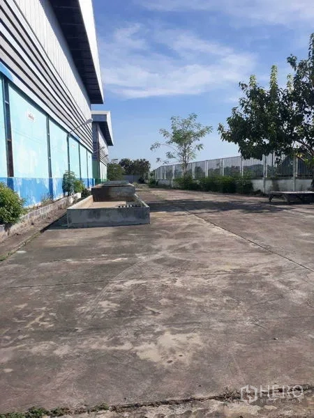 Factory for rent in Samut Prakan - Side access path with trees and greenery along the factory fence.