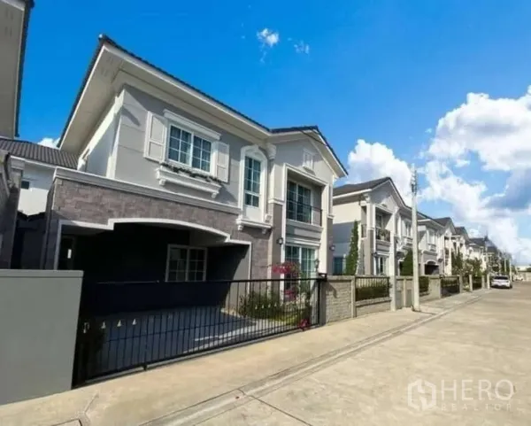 Detached House for sale in Bang Khen, Bangkok - Row of modern two-storey detached houses on a quiet gated street in Bang Khen, Bangkok under a bright blue sky.